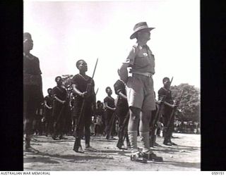 KILA, NEW GUINEA. 1943-10-24. GUARD OFFICER, WARRANT OFFICER H. P. KING, OFFICER IN CHARGE, NATIVE INVESTIGATION OFFICER, WITH THE GUARD OF HONOUR, ON PARADE AT THE NATIVE LABOUR CAMP WHILE BEING ..