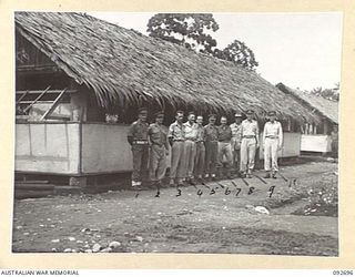 LAE AREA, NEW GUINEA. 1945-06-03. PERSONNEL OUTSIDE THE CARPENTER'S SHOP AT 112 CONVALESCENT DEPOT WHERE AN ARTS AND CRAFTS EXHIBITION IS BEING HELD. IDENTIFIED PERSONNEL ARE:- LIEUTENANT E.A. ..