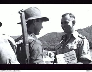 WAU AREA, NEW GUINEA. 1943-08-16. PRIVATE J. B. VINCENT, 2/5TH BATTALION, HANDS HIS VOTE IN THE FEDERAL ELECTION TO VX104163 LIEUTENANT T. A. FINLAYSON