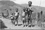 Man and children (showing signs of malnutrition) stand together near Rappaports' house in Tsembaga