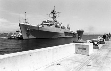 A commercial harbor tug maneuvers the miscellaneous flagship USS CORONADO (AGF-11), flagship for commander, Third Fleet, toward a pier at Naval Station, North Island. The CORONADO has arrived at its new home port after spending almost 20 years in Hawaii