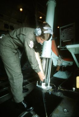 SGT. Debbie Whitacre, 54th Weather Reconnaissance Squadron, prepares to launch a dropsonde sensor from a WC-130 Hercules aircraft to measure a typhoon's speed and direction. The information will be relayed to the Joint Typhoon Warning Center (JTWC)