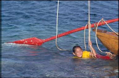 Child playing in water, with boat