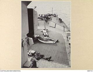 MADANG, NEW GUINEA. 1944-11-06. CREW MEMBERS TAKING A SHORT NAP ON THE FOREDECK ABOARD HMAS STAWELL