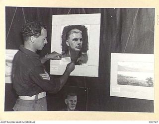 JACQUINOT BAY, NEW BRITAIN. 1945-06-05. SERGEANT L.S. PENDLEBURY, HEADQUARTERS 4 INFANTRY BRIGADE, LABELS ONE OF HIS NON COMPETITIVE ENTRIES IN THE OIL PAINTING CLASS DURING THE ARTS AND CRAFTS ..