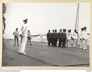 AT SEA OFF RABAUL, NEW BRITAIN. 1945-09-06. TWO MEMBERS OF THE ROYAL MARINES ARMED WITH SUBMACHINE GUNS, STAND GUARD BEHIND MEMBERS OF THE JAPANESE PARTY, DURING THE SURRENDER CEREMONY ON BOARD THE ..