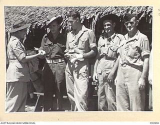 LAE, NEW GUINEA. 1945-06-09. PRIVATE K. LAURIE (2), RECEIVING SMOKES FROM THE RED CROSS SOCIETY REPRESENTATIVE. THE MEN, PATIENTS OF 2/7 GENERAL HOSPITAL ARE WAITING FOR TRANSPORT TO THE HOSPITAL ..