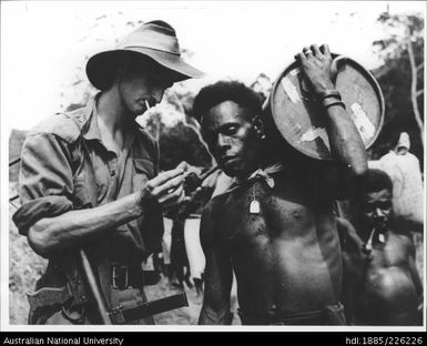 Australian soldier lighting the pipe of a Papua New Guinean during WWII