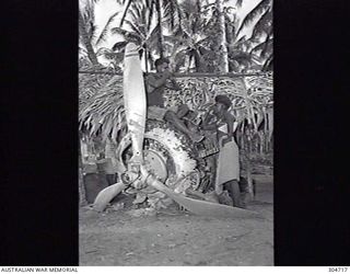 SEGI AREA, NEW GEORGIA, BRITISH SOLOMON ISLANDS PROTECTORATE. LOCAL NATIVES WITH A SALVAGED JAPANESE AIRCRAFT ENGINE. (NAVAL HISTORICAL COLLECTION)