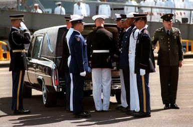 A joint services casket team stands at the back of a hearse, to take the casket of the Unknown Serviceman of the Vietnam Era and carry it aboard the frigate USS BREWTON (FF 1086). It will be transported by ship to Alameda, California, and then transferred to Arlington National Cemetery for interment at the Tomb of the Unknowns