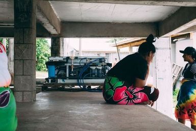 Two girls infront of broken water filter, Fakaofo, Tokelau