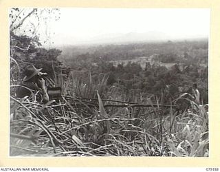 LAE, NEW GUINEA. 1945-03-11. AN ARMY OFFICER OPERATING A TELEPHONE SET "L" NO. 2 (AUST) IN AN ARTILLERY OBSERVATION POST