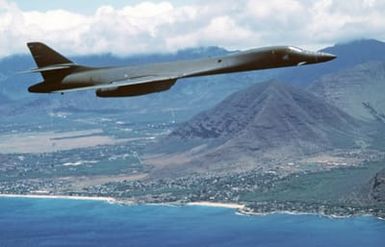 An air-to-air right side view of a B-1B aircraft in flight along the coastline of Hawaii during Exercise DISTANT MARINER. The aircraft is returning from Guam during its first deployment to the Pacific