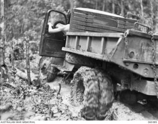 SOGERI, NEW GUINEA. 1943-11-20. A TIMBER HAULING TRUCK OF THE SCHOOL OF SIGNALS, NEW GUINEA FORCE MOVING ALONG A MUDDY JUNGLE TRACK TO PICK UP A LOAD OF LOGS FOR THE SAWMILL