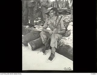 MOMOTE, LOS NEGROS ISLAND, ADMIRALTY ISLANDS. 1944-03-18. LEADING AIRCRAFTMAN L. J. BROWN, THE FIRST OF THE RAAF REINFORCEMENTS TO GET ASHORE, RESTS ON A LOG ON THE BEACH WHILE WAITING FOR OTHERS ..