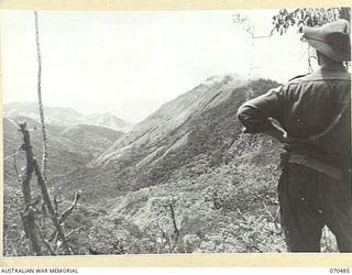 CRATER HILL, FINISTERRE RANGE, NEW GUINEA, 1944-02-16. A MEMBER OF THE 58/59TH INFANTRY BATTALION, VIEWING THE FARIA RIVER VALLEY FROM CRATER HILL. SHAGGY RIDGE LIES TO THE RIGHT, AND THE RAMU ..