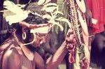 Decorated man holds up pearlshells and other valuables for ceremonial exchange