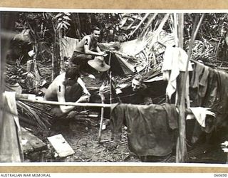 FINSCHHAFEN, NEW GUINEA. 1943-10-30. COMBINED SLIT TRENCH AND SLEEPING QUARTERS FAVOURED BY TROOPS OF THE 26TH AUSTRALIAN INFANTRY BRIGADE. SHOWN ARE LEFT TO RIGHT: NX69713 SIGNALMAN D. L. WRATHALL ..