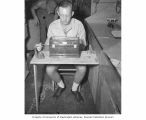 R. F. Foster weighing fish samples, probably in the vicinity of Bikini Atoll, 1947