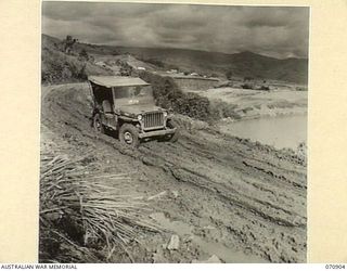 WAU - LAE ROAD, NEW GUINEA. 1944-02-26. SLIPPERY SHALE AND EARTH ROADWAY AFTER RAIN AT THE UPGRADE FROM SUNSHINE, 31 MILES FROM WAU. ABOUT A HUNDRED FEET BELOW THE ROAD SURFACE AND TO THE RIGHT OF ..