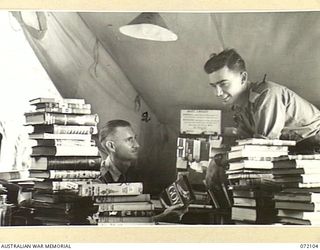 KILIGIA, NEW GUINEA. 1944-04-04. NX114455 SERGEANT B.J. LOCKE (2), AT ARMY EDUCATION SERVICE, HEADQUARTERS 5TH DIVISION, RECEIVING ASSISTANCE FROM QX28779 SERGEANT P.J. HORAN (1), IN SELECTING A ..