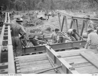 BOUGAINVILLE. 1945-05-01. SAPPERS OF 15 FIELD COMPANY, ROYAL AUSTRALIAN ENGINEERS, PLACING BEARERS INTO POSITION ON NEW AUSTPANEL BRIDGE ACROSS THE PURIATA RIVER. THIS AUSTRALIAN MADE BRIDGE IS ..