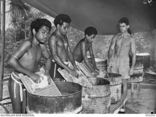 NEW GUINEA. C. 1944-02-17. AIRCRAFTMAN 1 C. MACBAYNE OF DRUMMOYNE, NSW, WITH THREE NATIVES AT WASH TUBS DOING THE HOSPITAL LAUNDRY