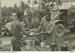 Madang, New Guinea. 1944-09-22. "Kai Time"! Members of a RAAF Marine Section, newly arrived at a New Guinea base wrested from the Japanese, line up for food at open air servery at No. 43 ..