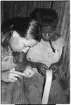 Shelley Schreiner plaits tokila armband, while Moruka works with a piece of bark