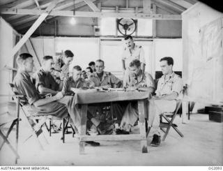 TOROKINA, BOUGAINVILLE ISLAND, SOLOMON ISLANDS. C. 1945-01-16. INTERIOR OF COMBINED OPERATIONS ROOM OF NO. 5 (ARMY CO-OPERATION) SQUADRON RAAF AND AIF SHOWING PERSONNEL DISCUSSING PLANS FOR A ..