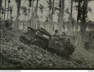 New Britain. 15 December 1943. A jeep ploughs its way through rough country climbing up a steep incline among the palm trees that fringe the Arawe Peninsula. The invading American forces soon ..