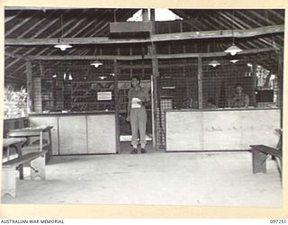 LAE, NEW GUINEA. 1945-09-11. CAPTAIN T.B. O'SHANESY, OFFICER COMMANDING CHARING CROSS EDUCATION CENTRE, IN THE DOORWAY OF HIS OFFICE. ARRANGEMENTS ARE BEING MADE BY THE LAE ART GROUP TO HOLD AN ART ..