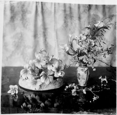 Frangipanni in low bowl beside mixed New Guinea flowers in a vase and a dog figurine, Rabaul, New Guinea, ca. 1929 / Sarah Chinnery