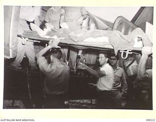 RABAUL, NEW BRITAIN, 1945-11-29. LANCE-CORPORAL N.R. FARLEY BEING LOADED ABOARD AN AIRCRAFT OF 1 MEDICAL AIR EVACUATION TRANSPORT UNIT FOR TRANSFER TO THE MAINLAND FROM 2/7 GENERAL HOSPITAL