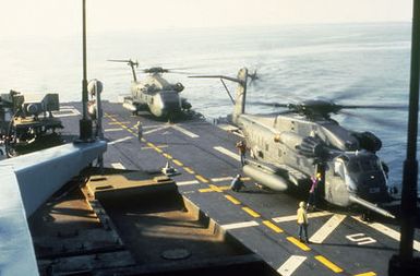 A CH-53E Super Stallion helicopter (foreground) and a CH-53 Sea Stallion helicopter on the flight deck of the amphibious assault ship USS GUAM (LPH-9) during operations off the coast of Beirut, Lebanon