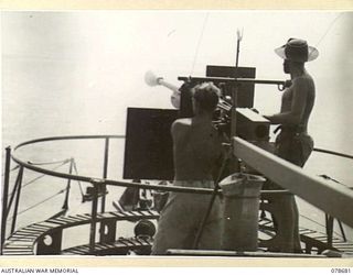 JACQUINOT BAY, NEW BRITAIN. 1945-01-24. LEADING SEAMAN WRIGHT (1) AND ABLE SEAMAN CONWAY (2) ABOARD THE ML802 FIRING THEIR 2 POUNDER AT THE OLD LCM (LANDING CRAFT MECHANISED) WHICH IS BEING USED AS ..