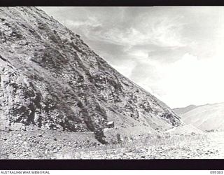 WAU-LABU ROAD, NEW GUINEA, 1945-12-13. A SECTION OF THE ROAD SKIRTING THE HILLS ALONG THE SNAKE RIVER. THE AREA IS MAINTAINED BY MEMBERS OF 8 MECHANICAL EQUIPMENT COMPANY