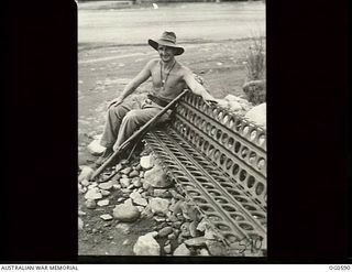 VIVIGANI, GOODENOUGH ISLAND, PAPUA. C. 1944. LEADING AIRCRAFTMAN F. H. EDELSTEN RAAF OF WARRNAMBOOL, VIC, RESTS ON HIS PARK BENCH MADE OF PSP (PIERCED STEEL PLATING, USED TO SURFACE AIRSTRIPS) IN ..