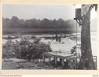 LAE AREA, NEW GUINEA, 1945-06-27. THE REMAINS OF THE COMMANDER-IN-CHIEF'S HUT, HEADQUARTERS FIRST ARMY SHOWING THE BATHROOM FOUNDATIONS AND HOT WATER SYSTEM WHICH WERE DAMAGED BY FLOODWATERS CAUSED ..