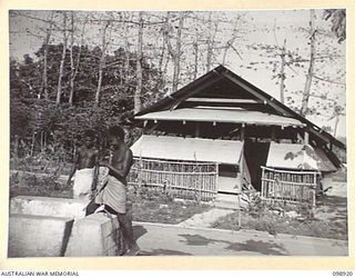 RABAUL, NEW BRITAIN. 1945-11-16. TWO BUKA NATIVES AT THE WELL OUTSIDE THE LIVING QUARTERS OF LIEUTENANT COLONEL MCLELLAN, BASE COMMANDER, HEADQUARTERS 5 BASE SUB AREA