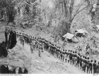 MUBO, NEW GUINEA, 1943-07-27. "THE VILLAGE SQUARE" 2/5TH BATTALION, QUARTERMASTER'S STORE WHERE GOODS ARE CHECKED FOR DESPATCH BY NATIVE CARRIERS TO THE FRONT LINE AT MOUNT TAMBU AND GOODVIEW. ..