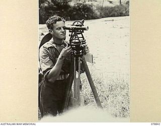 BOUGAINVILLE ISLAND. 1945-01-31. NX105298 BOMBARDIER G. LOVELL, 3RD SURVEY BATTERY, USING A THEODOLITE WHILE SURVEYING FOR AN AUSTRALIAN FIELD REGIMENT ON THE MAWARAKA- MOSIGETTA ROAD