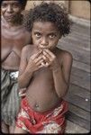 Young girl looks at camera, woman in background