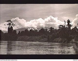 TAVERI RIVER, NEW GUINEA, 1943-09-05. LOOKING ACROSS THE TAVERI RIVER. THE CLOUD TOPPED MOUNTAIN RANGE IN THE BACKGROUND IS THE RANGE SURROUNDING THE ELOA BASIN AROUND WHICH THE MOUNTAIN SECTION OF ..