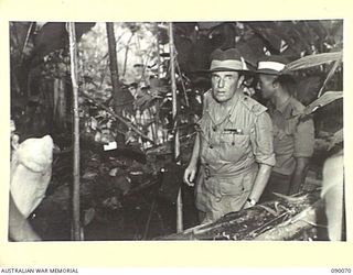 BOUGAINVILLE. 1945-03-30. LORD WAKEHURST, GOVERNOR OF NEW SOUTH WALES (2), WITH PRIVATE J.R. FROST (1), EXAMINING A BREN GUN PIT ON THE FRINGE OF THE PLATOON PERIMETER DURING AN EXERCISE IN THE ..