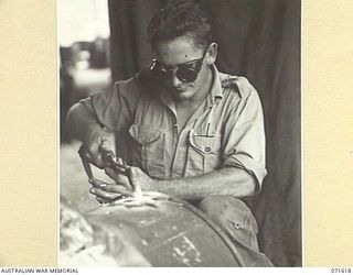 LAE, NEW GUINEA. 1944-03-24. NX161441 CORPORAL E. J. GRAHAM USING A CUTTING TORCH ON A DRUM IN THE WELDING SECTION AT THE AUSTRALIAN FORTRESS WORKSHOP