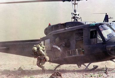 A member of the 1ST Bn., 35th Inf., 25th Inf. Div., exits a UH-1A Iroquois helicopter as an air-mobile assault takes place during Opportune Journey 4-83