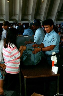 Sailors inspect the luggage of families arriving at a temporary evacuation center during Operation Fiery Vigil. The center was set up to process military dependents who were evacuated from the Philippines after volcanic ash from the eruption of Mount Pinatubo disrupted operations at Clark Air Base and Naval Station, Subic Bay.