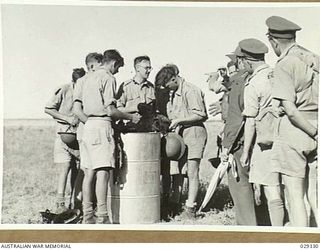 FORBES, AUSTRALIA. 1943-02. "GUINEA PIGS" TAKING PART IN A GAS SHELL EXPERIMENT DEPOSITING CONTAMINATED CLOTHING IN THE APPROPRIATE BINS TO BE TAKEN TO THE DECONTAMINATION POINT