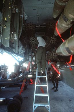 Members of the 43rd Bombardment Wing munitions loading team watch as three of their team members load general-purpose bombs aboard a B-52 Stratofortress aircraft during exercise Giant Warrior '89